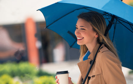 Woman holding a blue blank umbrella available in multiple styles for personal or promotional use