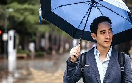 Business professional carrying a blue Fashion umbrella on a wet city street