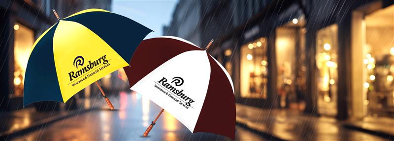Two golf umbrellas, one yellow and one white with a brand logo, held against a blurred city street background